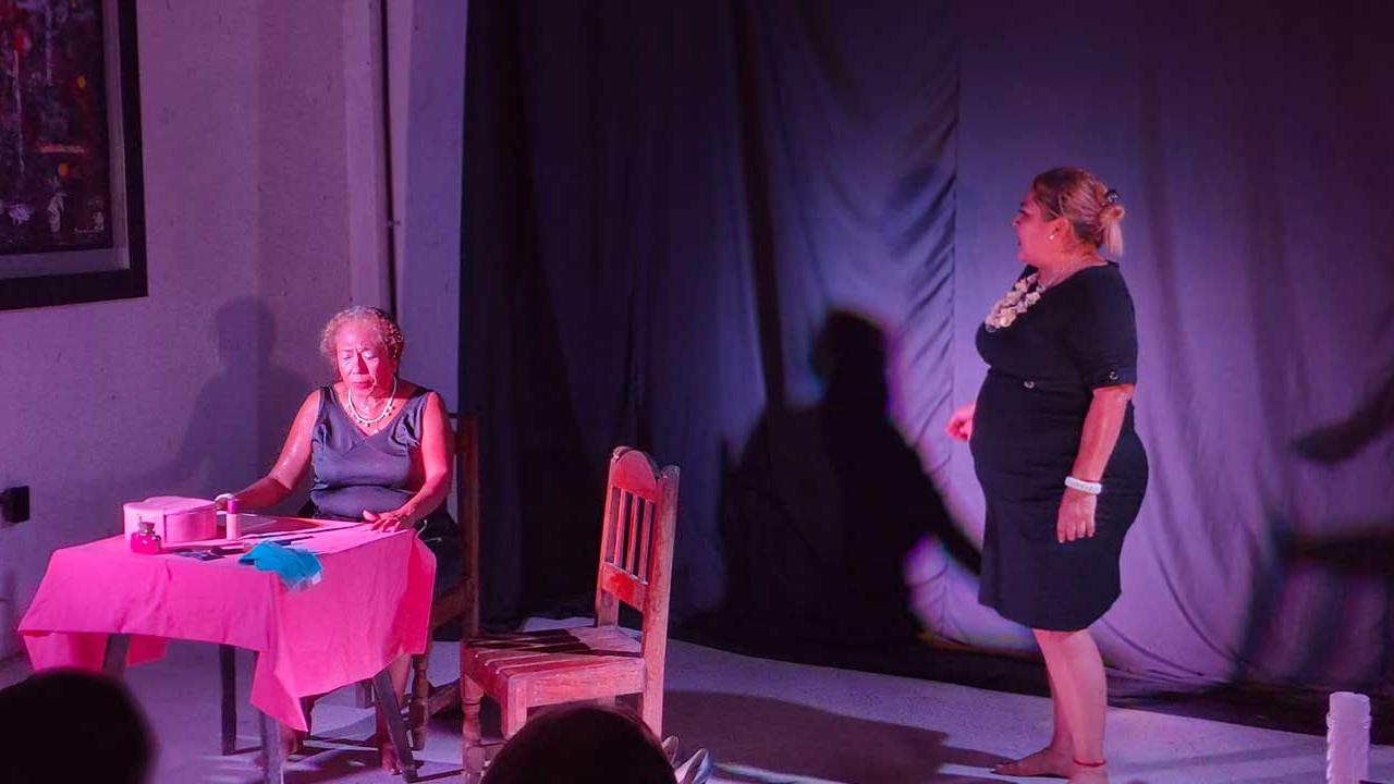 Actriz de pie confronta a su madre sentada y afligida durante una escena de la obra Las Ubarry, presentada por la Compañía de Teatro Cámara Negra en Acapulco.