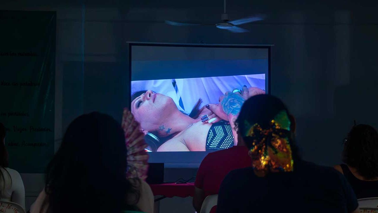 Personas asistentes al documental Kenya en Acapulco observan la escena en la que Kenya Cuevas yace en un ataúd durante una protesta por justicia para su amiga asesinada.