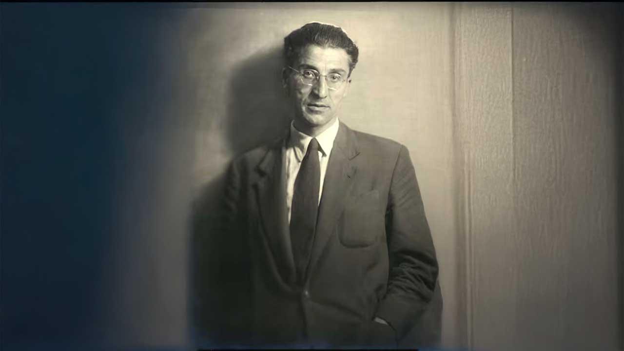 Fotografía en blanco y negro de Cesare Pavese, poeta y escritor italiano, vestido con traje formal y gafas, posando frente a una pared neutra. Imagen icónica que refleja su mirada introspectiva y su profunda conexión con la literatura del siglo XX.