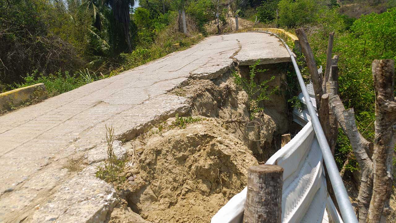 Vista del severo deslave en la calle Vicente Guerrero en Punta Maldonado, San Nicolás, mostrando el hundimiento de la tierra y una señalización improvisada con palos y láminas.