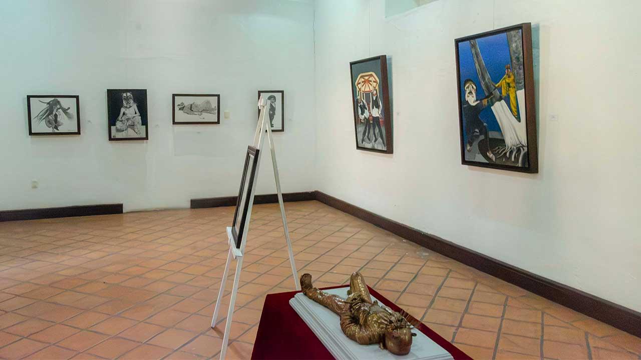 Vista panorámica de la exposición "Orgullo de mis raíces: Copanatoyac" en una sala del Museo Universitario José Juárez. Las pinturas de Miguel Altamirano Velázquez se exhiben en los muros junto con cédulas informativas, mostrando escenas inspiradas en la danza del Tekuanimej y las tradiciones de Copanatoyac, Guerrero.