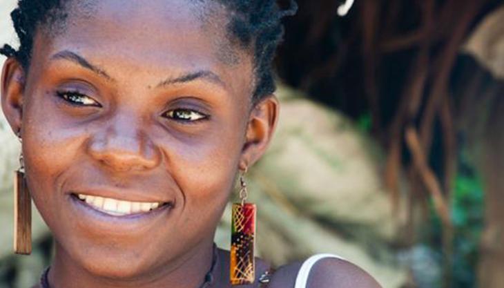 Rostro de mujer afrocolombiana sonriendo, con pendientes coloridos, retratada en un entorno natural