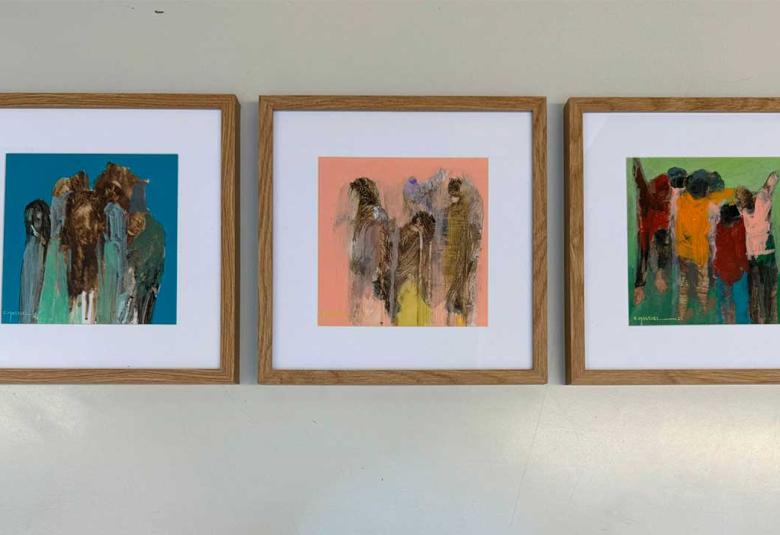 Tres obras pictóricas del artista guerrerense Héctor Massiel montadas en una pared blanca durante la exposición «Le Mexique en Couleurs» en el Teatro del Altigone, Francia. Las pinturas muestran figuras estilizadas y colores vibrantes sobre bastidores que conservan texturas orgánicas.