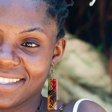 Rostro de mujer afrocolombiana sonriendo, con pendientes coloridos, retratada en un entorno natural