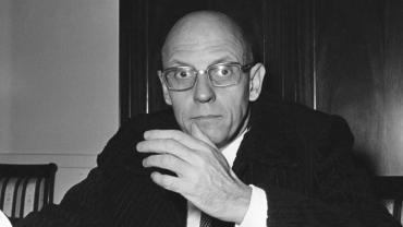 Retrato de Michel Foucault, filósofo francés, con gafas y una expresión pensativa.