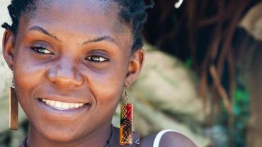 Rostro de mujer afrocolombiana sonriendo, con pendientes coloridos, retratada en un entorno natural